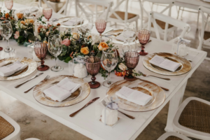 Reception table setting with mauve glassware and gold charger plates